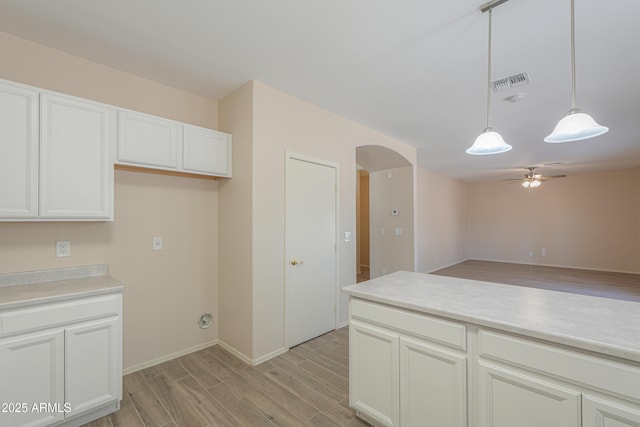 kitchen featuring arched walkways, pendant lighting, light countertops, and visible vents