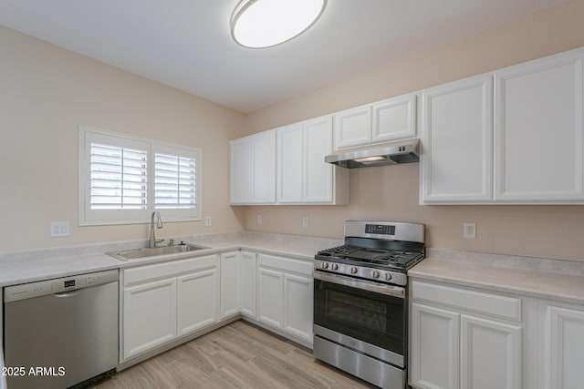 kitchen with under cabinet range hood, stainless steel appliances, a sink, white cabinets, and light countertops