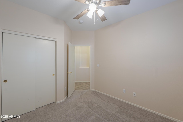 unfurnished bedroom featuring a ceiling fan, a closet, light colored carpet, and baseboards