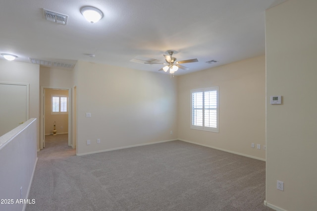 spare room featuring light carpet, ceiling fan, visible vents, and baseboards