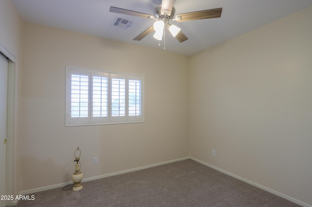 carpeted spare room with baseboards, visible vents, and a ceiling fan