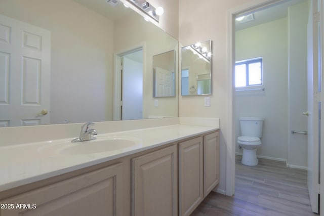 bathroom with wood finished floors, vanity, toilet, and baseboards