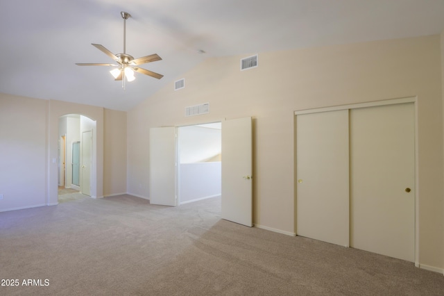 unfurnished bedroom with arched walkways, a closet, visible vents, and light carpet