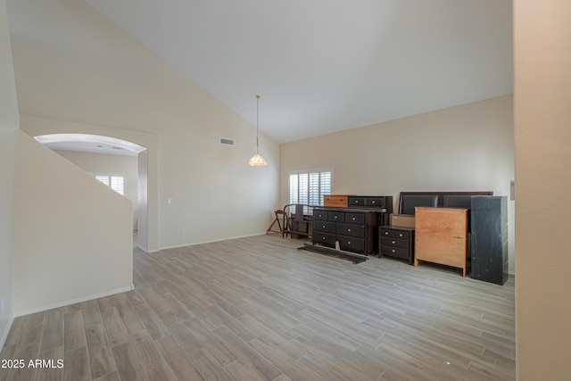 office area with high vaulted ceiling, light wood-type flooring, visible vents, and a healthy amount of sunlight