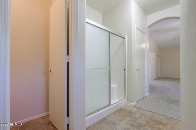 full bathroom featuring a shower stall and baseboards