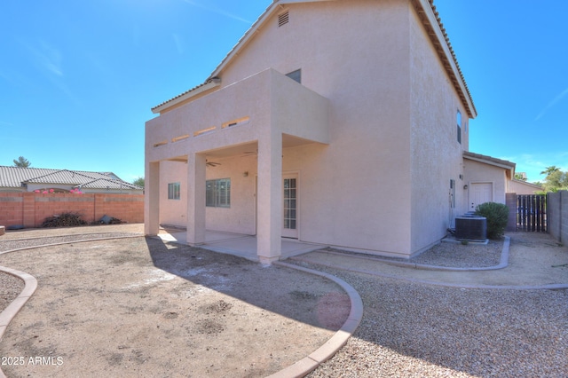 rear view of property with central AC, a patio area, a fenced backyard, and stucco siding