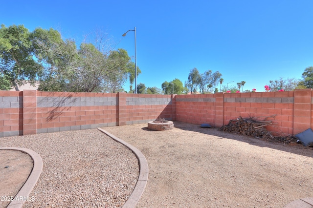 view of yard featuring a fenced backyard and a fire pit