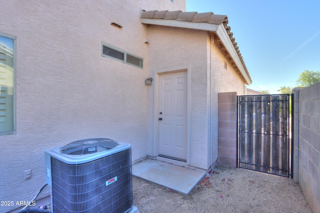 entrance to property featuring a tile roof, stucco siding, a gate, fence, and cooling unit