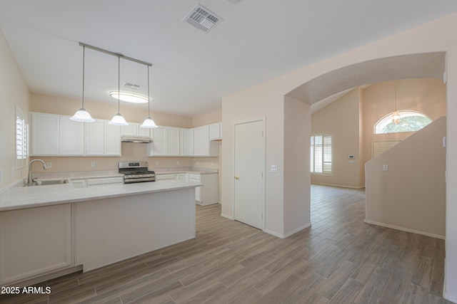 kitchen with light countertops, visible vents, stainless steel range with gas stovetop, a sink, and white cabinetry