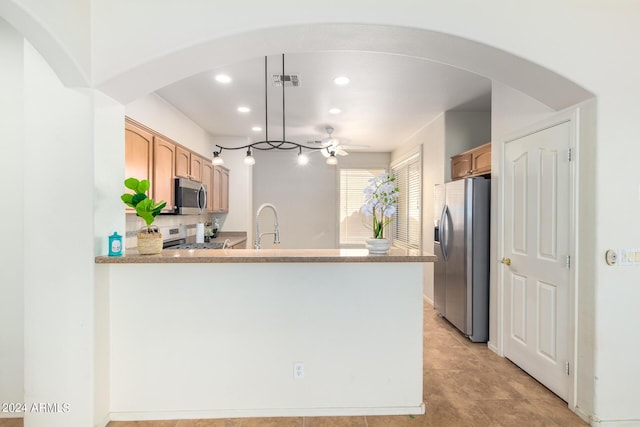 kitchen with light stone counters, light tile patterned floors, kitchen peninsula, pendant lighting, and stainless steel appliances