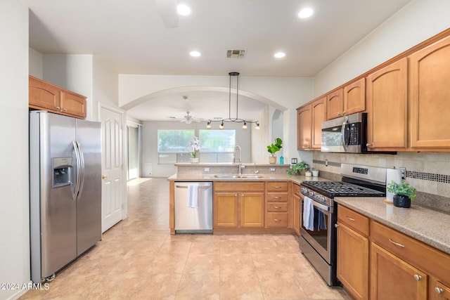 kitchen with sink, stainless steel appliances, tasteful backsplash, decorative light fixtures, and kitchen peninsula