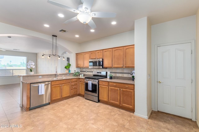 kitchen featuring appliances with stainless steel finishes, sink, pendant lighting, and kitchen peninsula