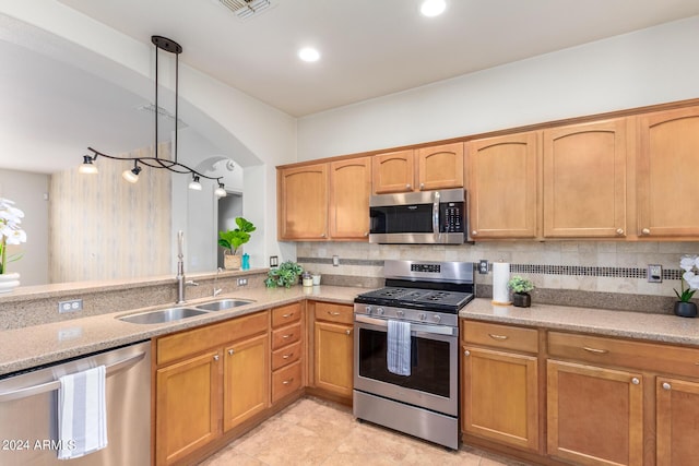 kitchen featuring appliances with stainless steel finishes, pendant lighting, tasteful backsplash, sink, and light stone counters