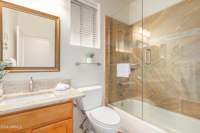 full bathroom featuring vanity, combined bath / shower with glass door, and toilet