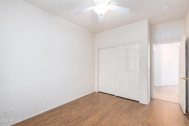 unfurnished bedroom with ceiling fan, wood-type flooring, and a closet