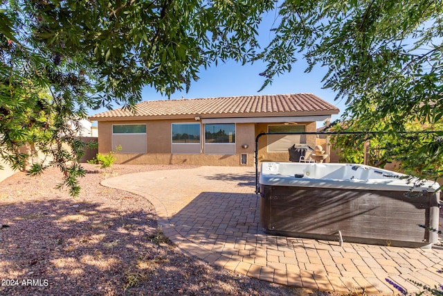 rear view of property with a hot tub and a patio