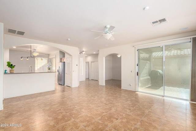 unfurnished living room featuring ceiling fan with notable chandelier