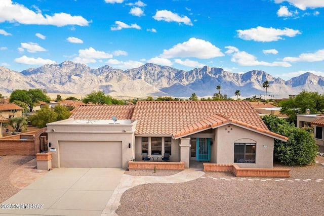 mediterranean / spanish home with stucco siding, a tiled roof, a garage, driveway, and a mountain view