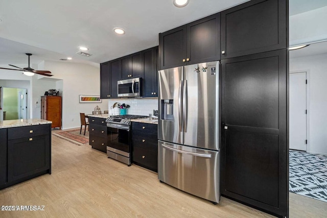 kitchen featuring recessed lighting, dark cabinets, light wood-style flooring, stainless steel appliances, and visible vents