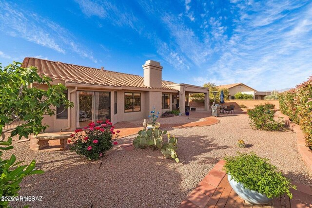 rear view of house featuring a chimney, a fenced backyard, stucco siding, a patio, and a tile roof