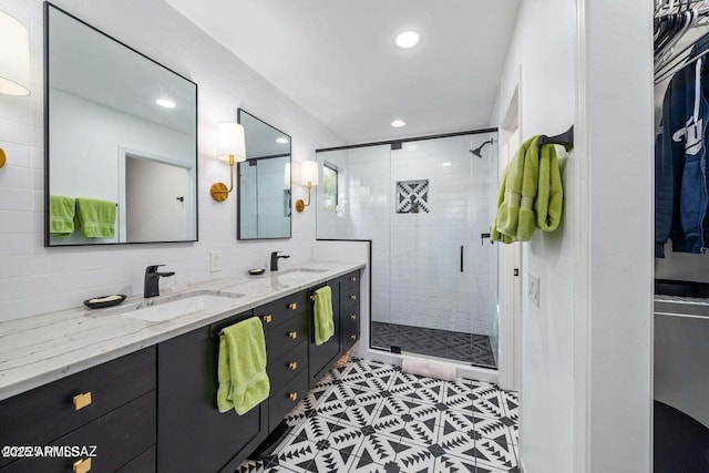 full bathroom with recessed lighting, double vanity, a sink, and a shower stall