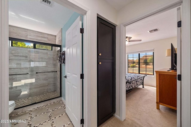 corridor with visible vents, baseboards, and light carpet