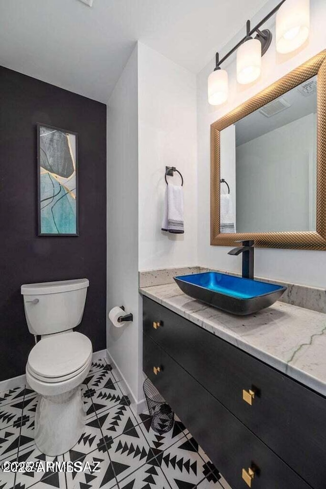 bathroom with toilet, tile patterned flooring, vanity, and baseboards