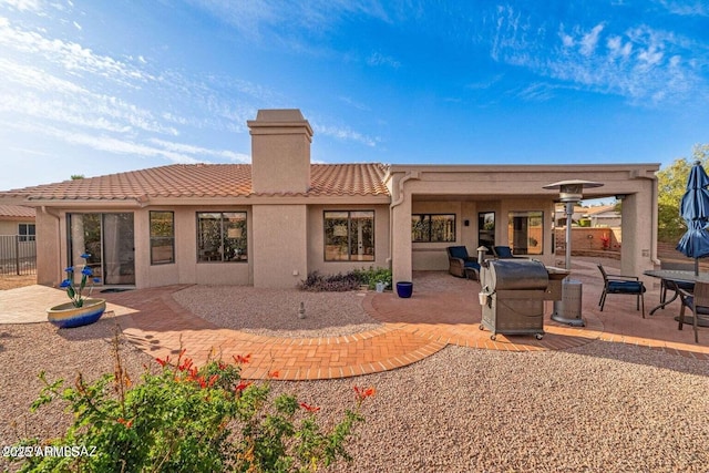 rear view of property featuring fence, a tile roof, a chimney, a patio area, and stucco siding