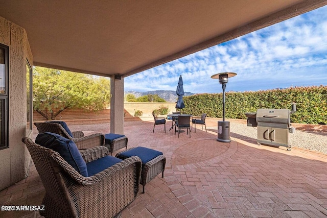 view of patio featuring a mountain view, area for grilling, outdoor dining space, and fence