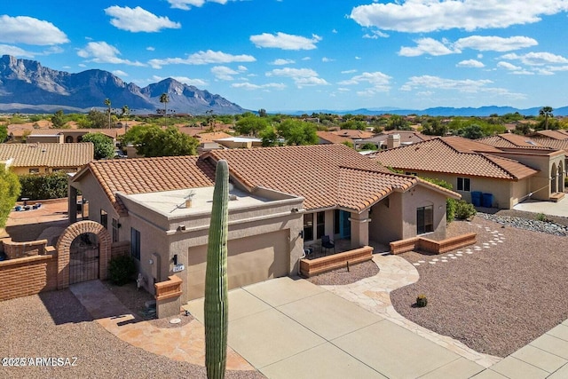 mediterranean / spanish house with a gate, a mountain view, stucco siding, and an attached garage