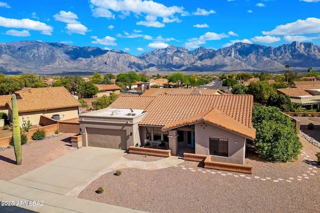 mediterranean / spanish-style house featuring a tile roof, a garage, a mountain view, driveway, and stucco siding