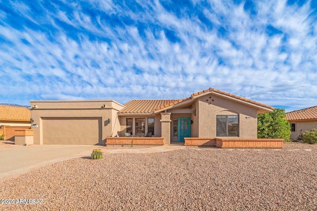 view of front of home featuring driveway, a garage, stucco siding, and a tiled roof