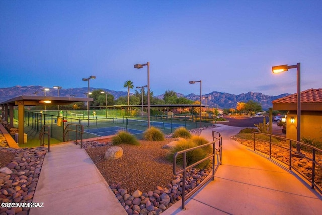 view of property's community with a tennis court, fence, and a mountain view