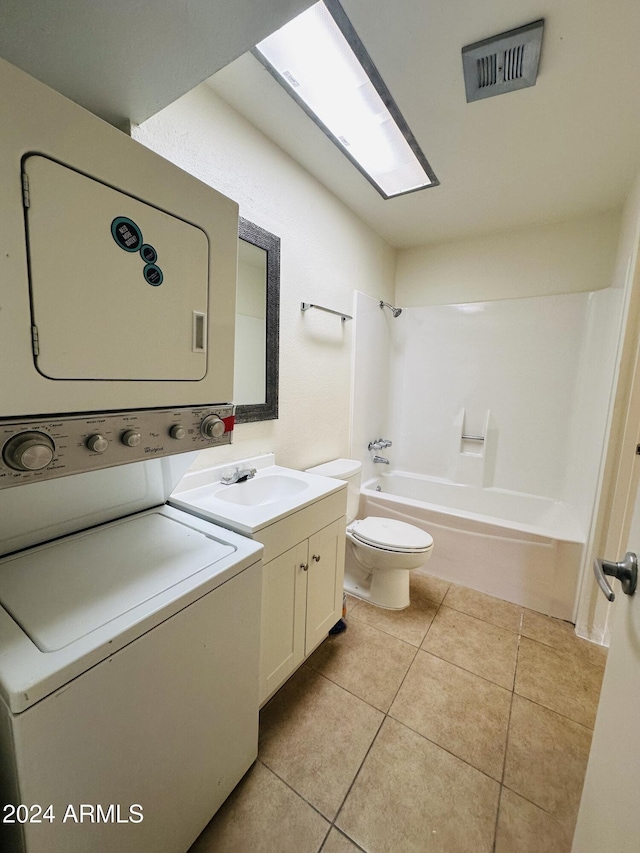 clothes washing area with sink, light tile patterned flooring, and stacked washing maching and dryer