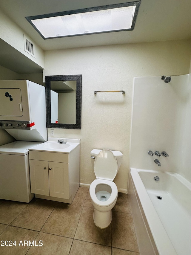 full bathroom featuring tile patterned floors, tub / shower combination, vanity, toilet, and stacked washer / drying machine