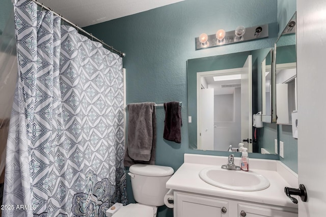 bathroom featuring a textured wall, vanity, toilet, and a shower with curtain