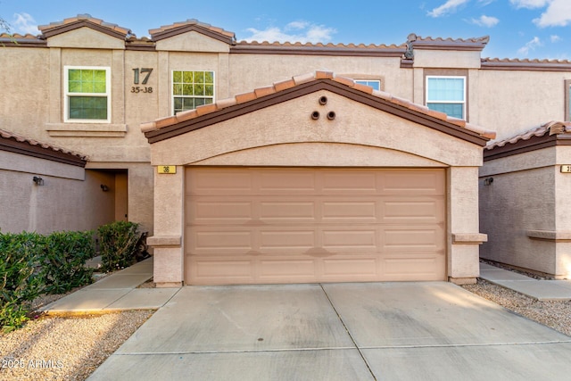 multi unit property featuring a tile roof, driveway, and an attached garage