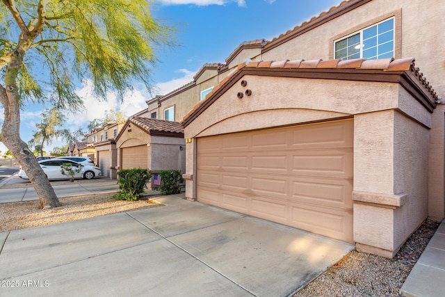 view of front of home featuring stucco siding, a tile roof, and driveway