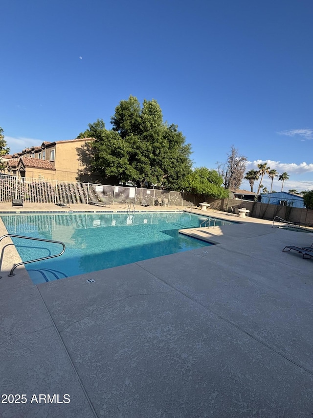 community pool with fence and a patio