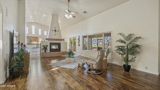 living area featuring a wealth of natural light, dark wood-style flooring, visible vents, and a fireplace