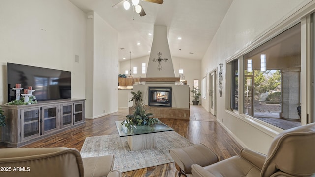 living area featuring dark wood-style floors, a ceiling fan, a multi sided fireplace, high vaulted ceiling, and baseboards