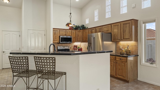 kitchen featuring dark countertops, a kitchen island with sink, and stainless steel appliances