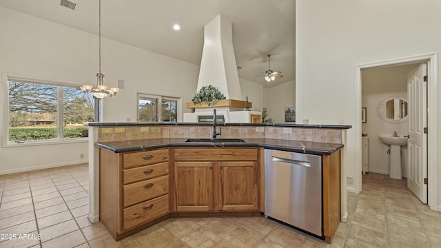 kitchen featuring ceiling fan with notable chandelier, a sink, stainless steel dishwasher, brown cabinets, and an island with sink