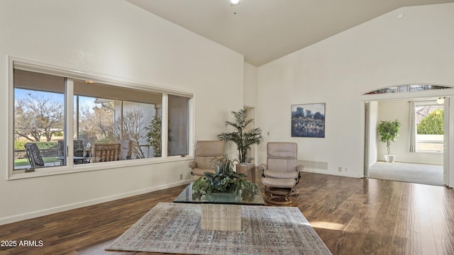 living area featuring high vaulted ceiling, dark wood-style flooring, and baseboards