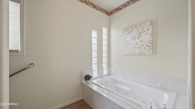 bathroom with tile patterned flooring, baseboards, and a tub with jets