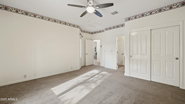 unfurnished bedroom with a closet, light colored carpet, visible vents, attic access, and a ceiling fan