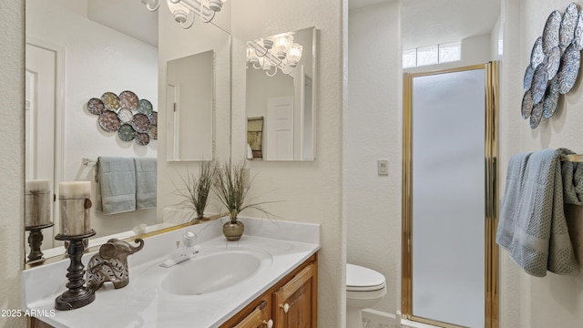 full bathroom with toilet, a textured wall, a stall shower, and vanity