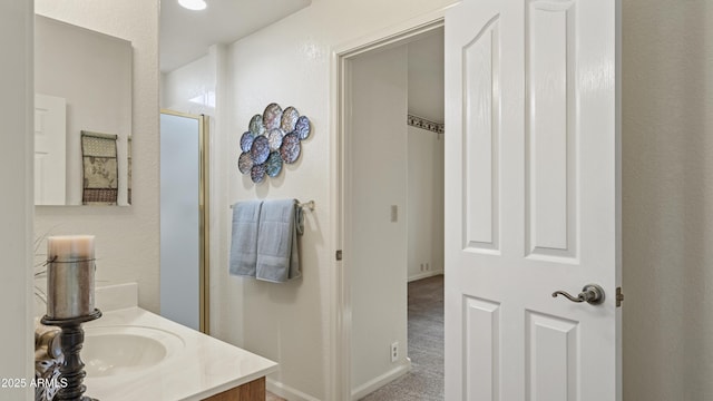 bathroom featuring a stall shower, vanity, and baseboards