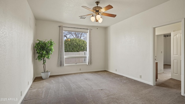 unfurnished room featuring a textured ceiling, a textured wall, a ceiling fan, baseboards, and carpet