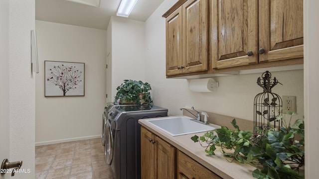 laundry room featuring washing machine and dryer, cabinet space, a sink, and baseboards